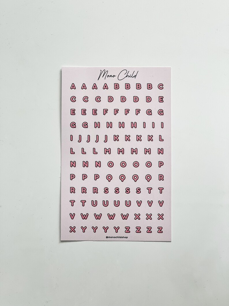 May include: A pink card with the text "Mono Child" at the top and a grid of pink letter stickers. The letters are outlined in a darker pink. The bottom of the card has the text "@monochildshop".