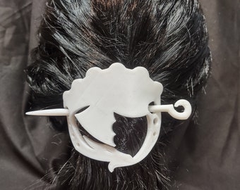 May include: White plastic hair stick with a decorative design. The stick is shaped like a stylized bird with a curved tail and a small loop at the end.