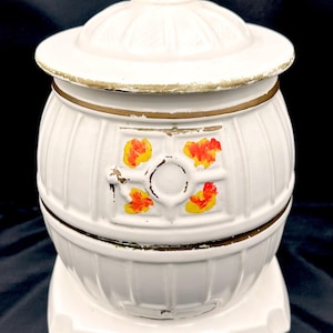 May include: A white ceramic mug with a black handle and the text "But First, Coffee" in a black, handwritten-style font. The mug is on a white surface.