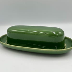 May include: A white ceramic mug with a black handle and the text "But First, Coffee" in a bold, black font. The mug is set against a neutral background, highlighting its simple design.