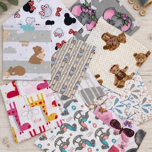 Op de afbeelding: Een verzameling vierkante stofstalen met diverse patronen, waaronder Minnie Mouse-silhouetten, olifanten met bloemenkransen, teddyberen, giraffen en vlinders. De prints bevatten teksten zoals mama bear en hello baby.