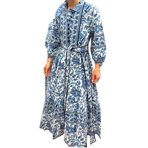 May include: A long, blue and white floral print dress with a button-up front and a matching belt. The dress has a slightly puffed sleeve and a flowing skirt.