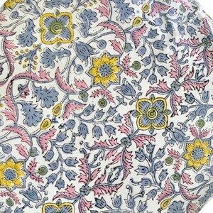 May include: White fabric with a floral pattern in shades of pink, blue, and yellow. The pattern features intricate designs of leaves, flowers, and vines.