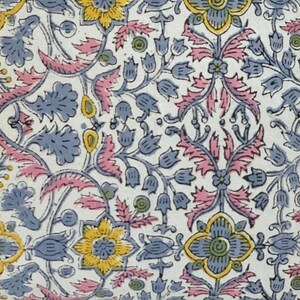 May include: A white fabric with a repeating floral pattern. The flowers are blue, yellow, and pink. The pattern is intricate and detailed.