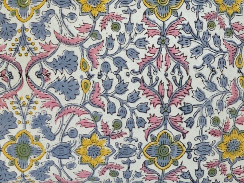 May include: A white fabric with a repeating floral pattern. The flowers are blue, yellow, and pink. The pattern is intricate and detailed.