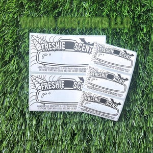 May include: Four white labels with black text and graphics. The labels read "Freshie Scent" and include instructions to hang the item immediately, keep away from children and pets, and to avoid extreme temperatures.