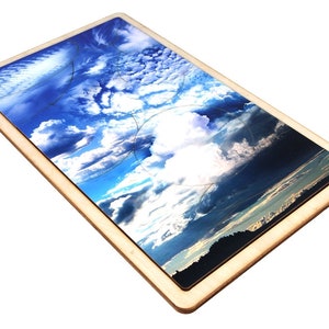 May include: A wooden puzzle with a framed image of a blue sky with white clouds. The puzzle is made of multiple pieces that fit together to create the image.