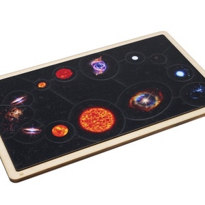May include: A wooden game board with a black background and a variety of colorful images of stars, galaxies, and nebulae. The board is surrounded by a light brown wooden frame.