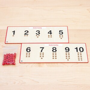 May include: Two wooden boards with the numbers 1 through 10 printed on them. Each number has a corresponding number of holes drilled into the board. A small plastic bag filled with red counting beads is in the lower left corner of the image.