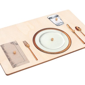 May include: A wooden puzzle with a place setting, including a plate, fork, knife, spoon, napkin, and glass. The puzzle pieces are held in place with wooden pegs.