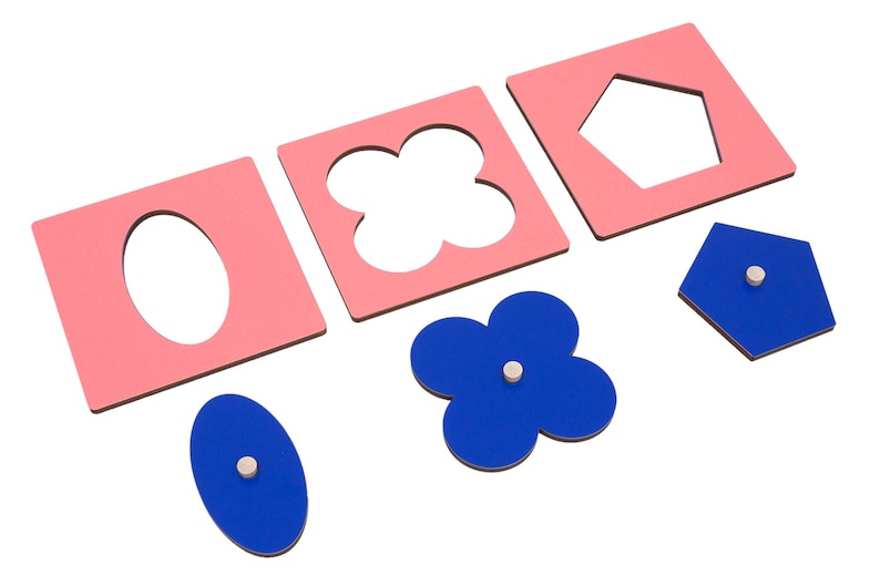 May include: A set of pink and blue wooden shape puzzle pieces. The pink pieces have cutouts of an oval, a four-leaf clover, and a pentagon. The blue pieces are solid shapes that fit into the cutouts.
