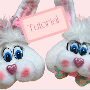 Könnte beinhalten: Zwei weiße Plüsch-Hasenköpfe mit rosa Ohren und Nasen. Ein Hase hat eine rosa-grüne Schleife und der andere eine grün-rosa Schleife. Der Text "Tutorial" steht auf einem rosa Rechteck.