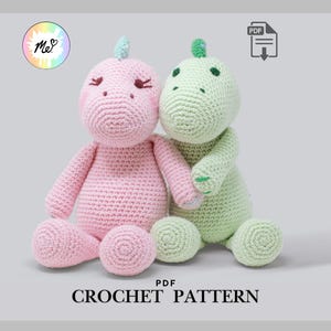 Peut inclure: Deux poupées dinosaures crochetées, une rose et une verte, sont assises côte à côte. Le dinosaure rose a une corne bleu clair et le vert a une corne verte. Les poupées sont faites à la main et le texte "CROCHET PATTERN" est en bas.