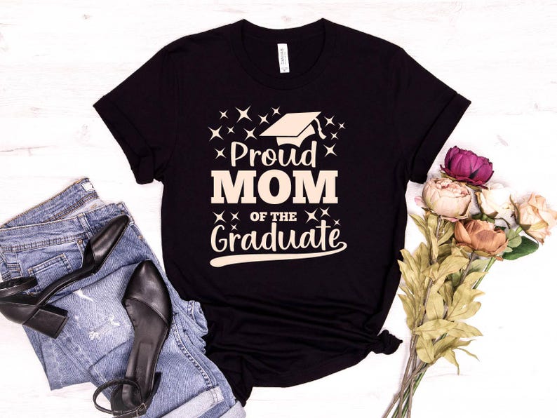 May include: Black t-shirt with a white graphic that says "Proud Mom of the Graduate" with a graduation cap icon.