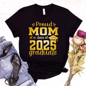 May include: Black t-shirt with gold text that reads "Proud Mom of a class of 2025 graduate".