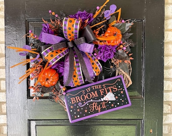 May include: A Halloween wreath with a black, orange, and purple color scheme. The wreath features a large bow with polka dots, small pumpkins, and a sign that reads "If the broom fits... Fly it."