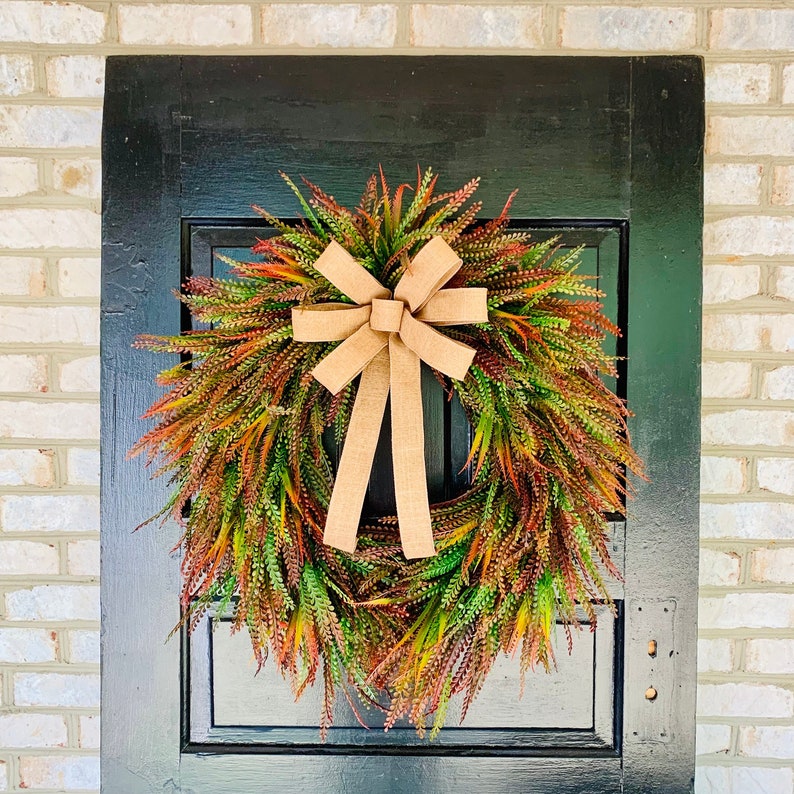This Fall wreath is built on a 18" grapevine. There is an abundance of artificial bead grass and sword fern grass nestled into this grapevine. There is a beautiful bow attached to this Fall grapevine wreath that is made using 1.5" wired ribbon.