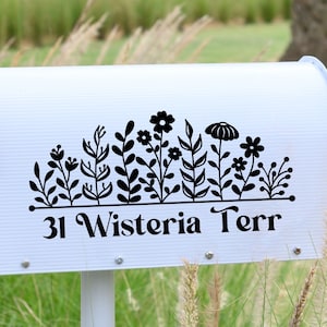 May include: White mailbox with a black floral design and the address "31 Wisteria Terr" printed below. A red flag is attached to the mailbox.