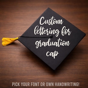 May include: Black graduation cap with gold tassel. The cap features the text "Custom lettering for graduation cap" in white script. The bottom of the image reads "PICK YOUR FONT OR OWN HANDWRITING!"
