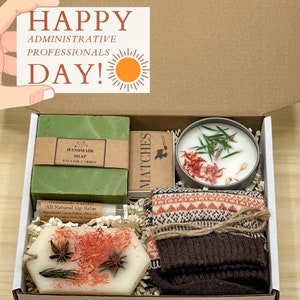 May include: A gift box containing a green bar of handmade soap, a candle, matches, lip balm, and patterned socks. The soap is labeled "English Garden." The box also includes a decorative wax piece and the text "HAPPY ADMINISTRATIVE PROFESSIONALS DAY!"