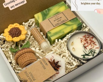 Op de afbeelding: Een geschenkdoos gevuld met handgemaakte items. Inclusief citroenverbena zeep, lippenbalsem, een kaars, een bijenwas zakje, en een gehaakte zonnebloem en eikel. De doos bevat ook een gepersonaliseerde wenskaart.