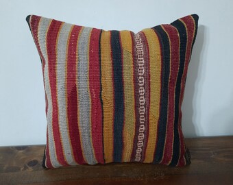 May include: A striped throw pillow with red, yellow, black, and gray stripes. The pillow is made of a woven fabric and has a rustic, vintage look.