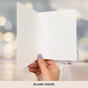 May include: A blank white card with a folded edge, held by a hand against a blurred background of white and blue lights. The text "BLANK INSIDE" is printed below the card.