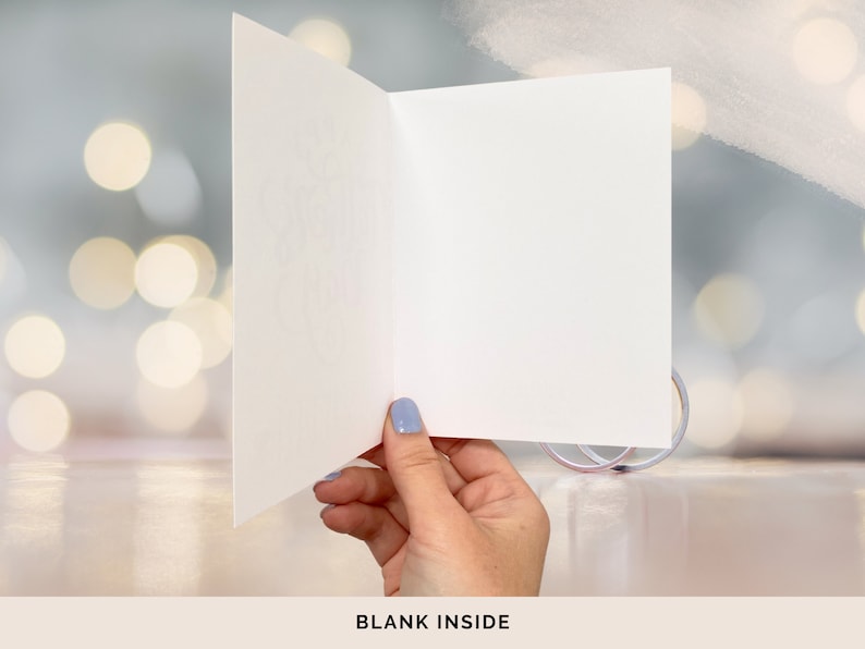 May include: A blank white card with a folded edge, held by a hand against a blurred background of white and blue lights. The text "BLANK INSIDE" is printed below the card.