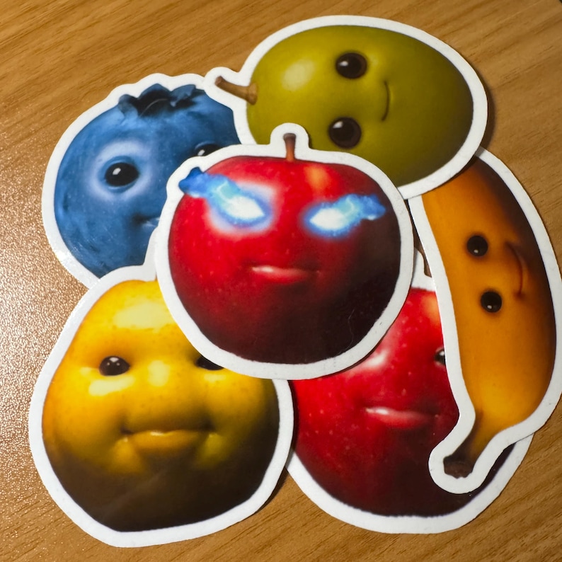 Puede incluir: Una colecci&oacute;n de pegatinas de frutas con caras sonrientes. Incluye un ar&aacute;ndano azul, una pera verde, una manzana roja con ojos brillantes, una pera amarilla, un pl&aacute;tano amarillo y otra manzana roja.