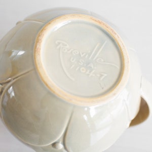 May include: A light gray ceramic bowl with a floral design. The bottom of the bowl has the text "Rareville U.S.A. 11044-7" printed on it.