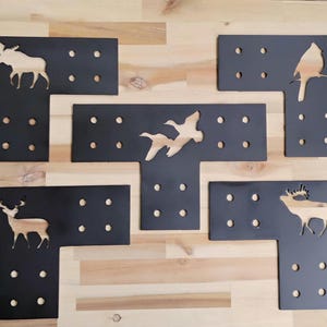 May include: Five black metal T-shaped brackets with different animal cutouts. The cutouts include a moose, a cardinal, a pair of geese, a deer, and an elk.