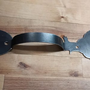 May include: A metal door handle with a rooster design. The handle is made of black metal and has a round base with two holes for mounting.