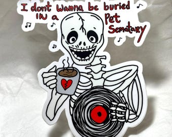 Peut inclure: Un squelette de dessin animé tenant une tasse de café avec un cœur brisé et un disque vinyle. Le squelette sourit et le texte dit "Je ne veux pas être enterré dans un cimetière pour animaux".