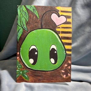 May include: A green cartoon character with large eyes and a pink heart above it. The character is drawn on a brown background with green leaves and brown stripes.