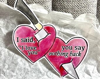 May include: Two pink hearts pierced by a knife. The text on the hearts reads "I said, "I love you"... you say nothing back."