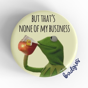 May include: A green Muppet character, Kermit the Frog, is drinking from a glass of iced tea. The text on the button reads "But that's none of my business".