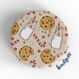 May include: A round button with a beige background and a pattern of milk bottles with straws, chocolate chip cookies, and candy canes. The text "badgriss" is in blue at the bottom right corner.