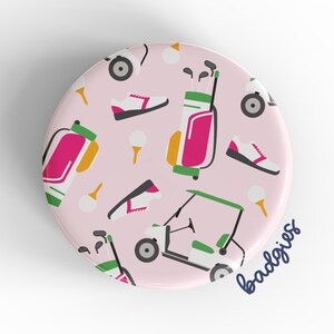 May include: Pink round button with a golf-themed pattern. The pattern includes golf carts, golf bags, golf balls, and golf shoes. The text "badgigs" is in the lower right corner.
