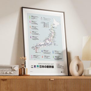 May include: Framed map of Japan's Shinkansen railway system, featuring a light blue background with detailed route information. The map includes Japanese text and icons, with the title "Japan Shinkansen Map" at the bottom. The framed print is displayed on a wooden cabinet.