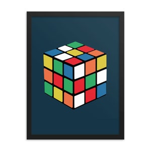 Może przedstawiać: Oprawiony wydruk artystyczny przedstawiający kolorową kostkę Rubika na ciemnoniebieskim tle. Kostka jest oddana w jasnych, jednolitych kolorach, w tym czerwonym, żółtym, niebieskim, zielonym, pomarańczowym i białym. Wydruk jest oprawiony w czarną ramę.