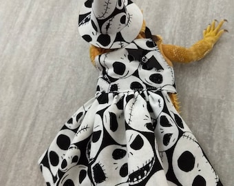 Puede incluir: Un vestido estampado en blanco y negro con un sombrero de bruja con un diseño de Jack Skellington. El vestido tiene un fondo negro con caras blancas de Jack Skellington.
