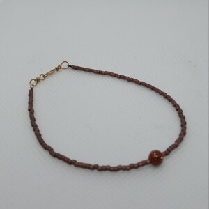 Matte copper beaded bracelet with goldstone bead. Gold hook and eye closure seed beaded. 7 3/8 inches long.