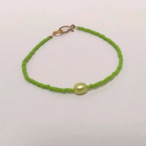 Dainty green seed bead and fresh water pearl bracelet with gold hook. 7/14 inches long.