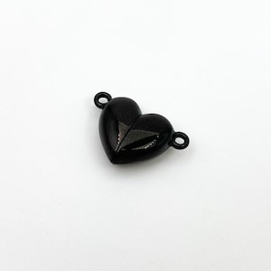 May include: Black heart-shaped metal connector with two loops. The connector is designed to be used for jewelry making.