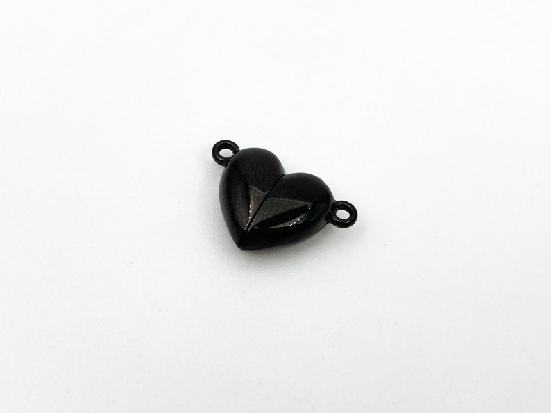 May include: Black heart-shaped metal connector with two loops. The connector is designed to be used for jewelry making.