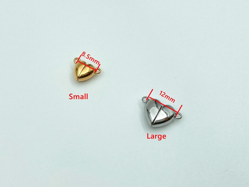 May include: Two gold-tone heart-shaped magnetic clasps for jewelry making. The smaller clasp measures 8.5 mm and the larger clasp measures 12 mm.