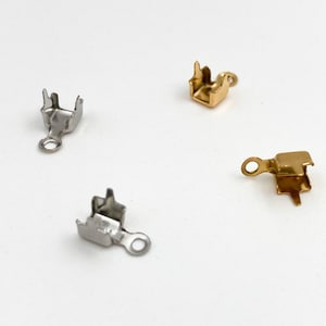 May include: Three metal clasps for jewelry making. One is silver, one is gold, and one is a side-view of a gold clasp.