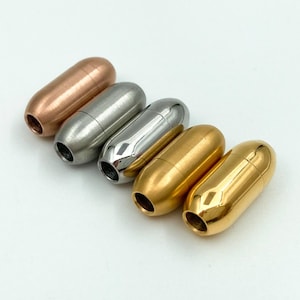 May include: Five metal cord ends in different finishes: rose gold, silver, gold, and two gold finishes. The cord ends are cylindrical and have a smooth, polished finish.