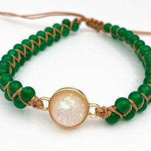 May include: A green beaded bracelet with a gold-toned clasp and a white opal-like stone in the center.