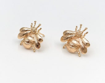 May include: A pair of gold bee earrings. The bees are detailed and have textured wings.